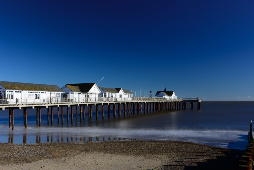 Southwold Pier.  Dark blue sky meets the blue sea.  The pier stretches out from left to right.