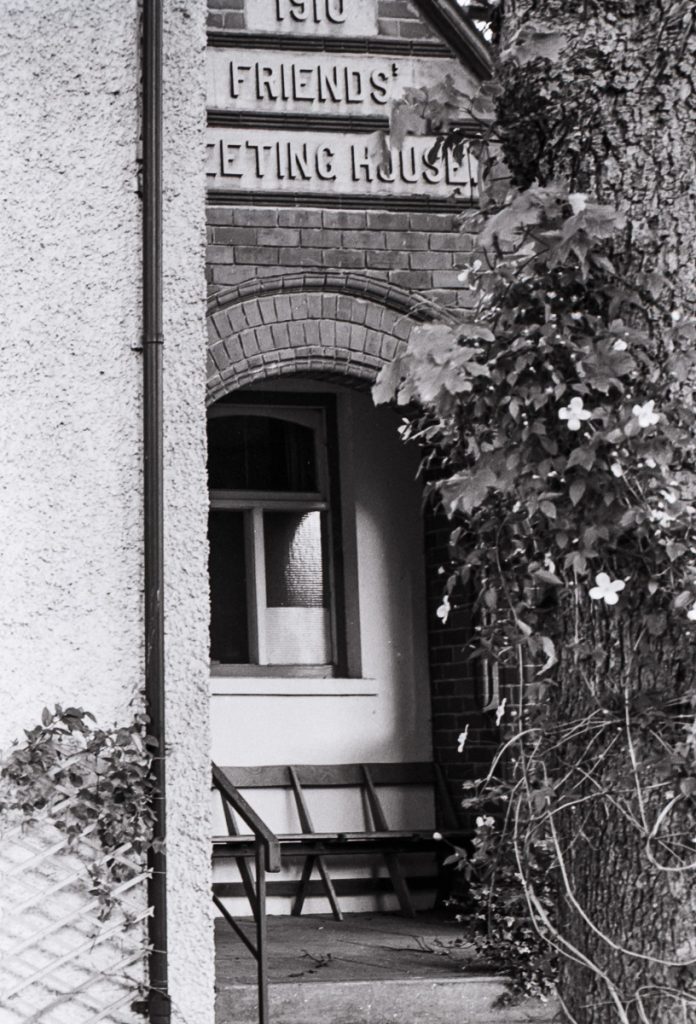 A black and white film photograph of the friends meeting house in Lincoln.  The archway leading to the door is in the picture.