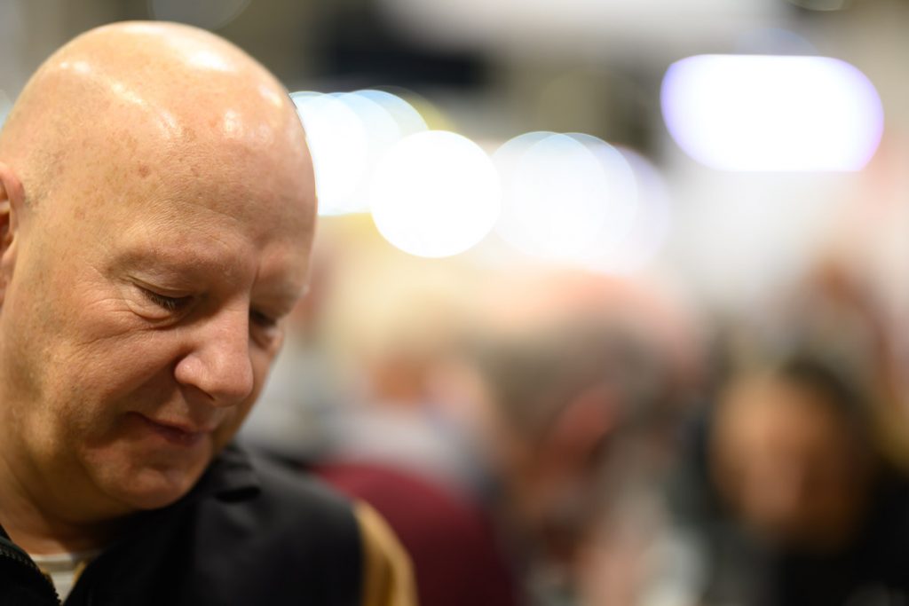 Portrait at a trade stand taken with a Nikkor 85mm f/1.2 lens wide open.