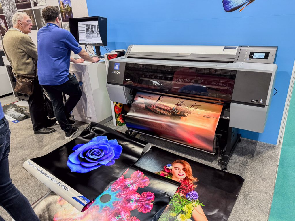 Epson large format printer.  A computer is at the side and a Epson representative is showing a customer how to use the printing software.