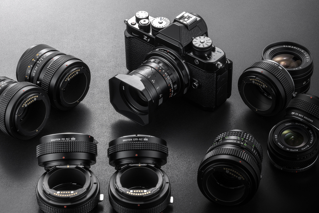 Advertising shot showing a selection lens adapters. A black Nikon Zf is centre frame.