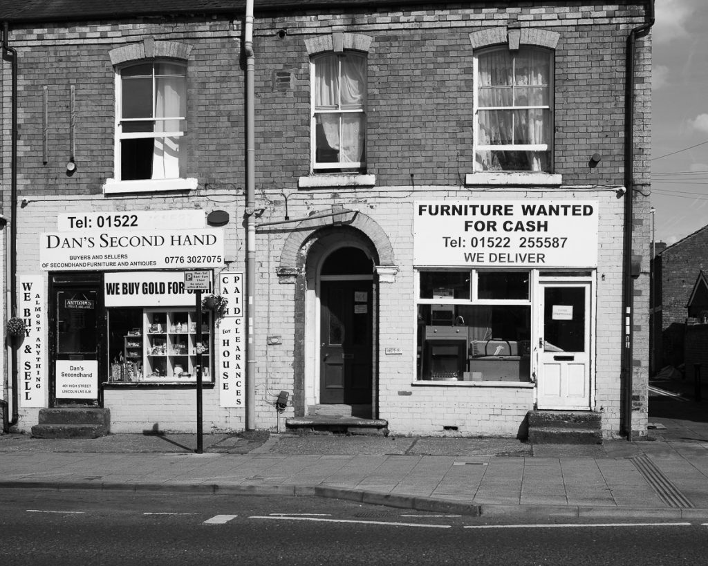 An old high street terrace house. Two shops in the ground floor of two of them, both second hand shops.
