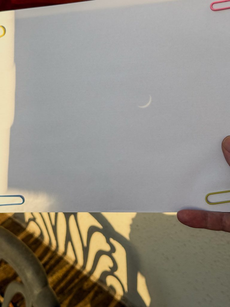 Piece of white paper, with a project from a pinhole showing the eclipse of the sun