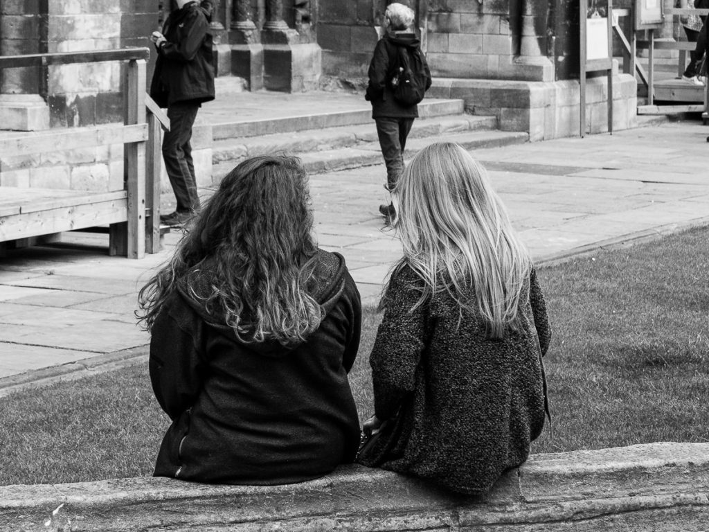 Two woman sat on wall in front of Cathedral.