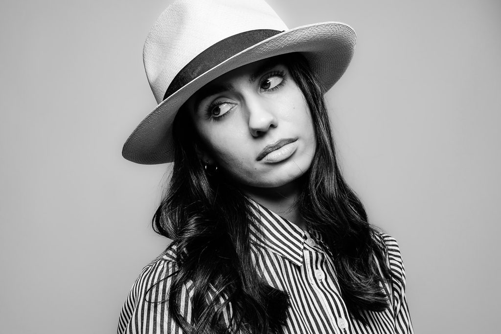 Model Dina in striped blouse and white Panama hat, looking camera left away from camera.